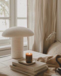 A beige lamp on top of the table next to books and an ash candle, scandinavian interior design, modern home decor, aesthetic. The lamp is in the style of scandinavian interior design. --ar 46:57 --style raw Job ID: e85c905b-13f3-4f9b-a221-f3f8ea3581bd